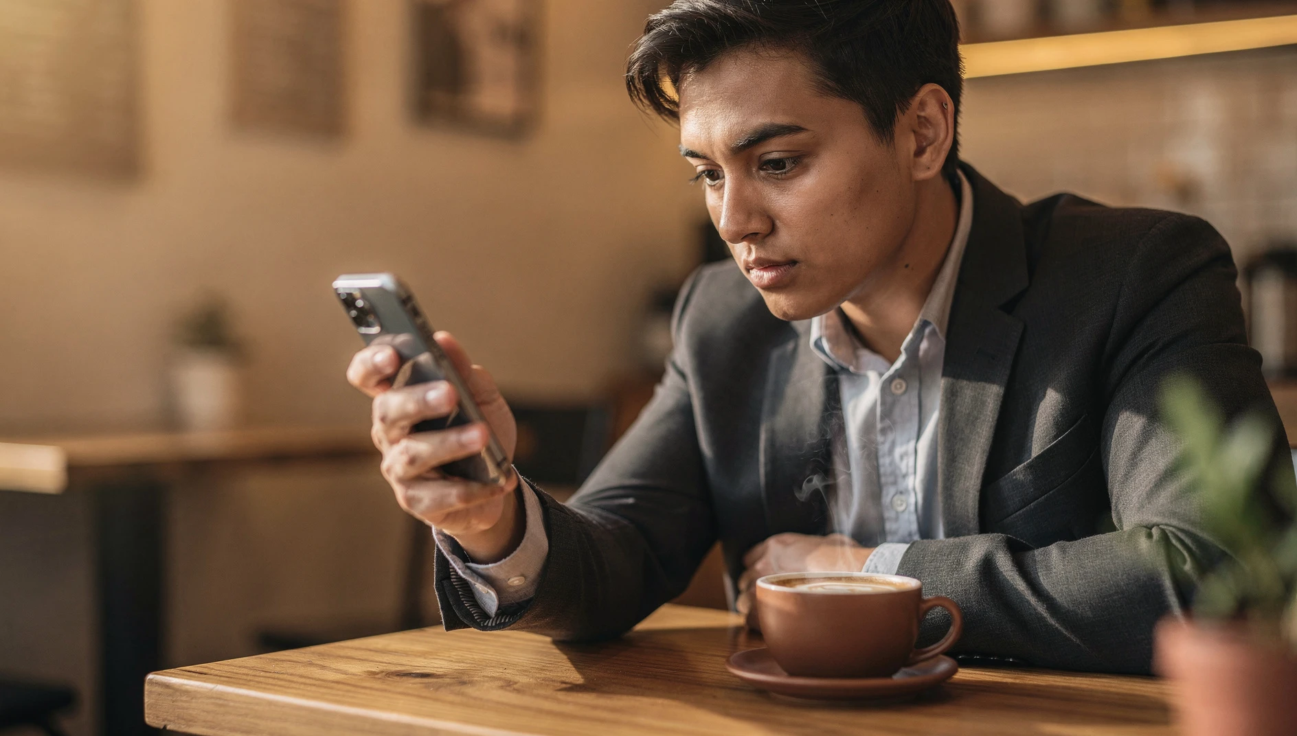 A person reviewing notes and a task list on a phone at a coffee shop with warm café light