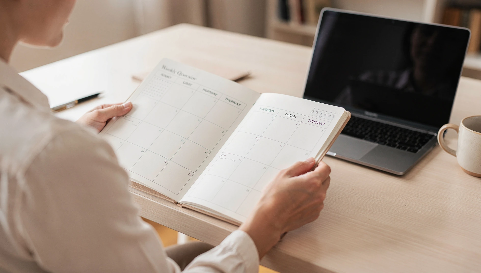 A professional reviewing a weekly calendar planner at a bright home office desk with a laptop in morning light