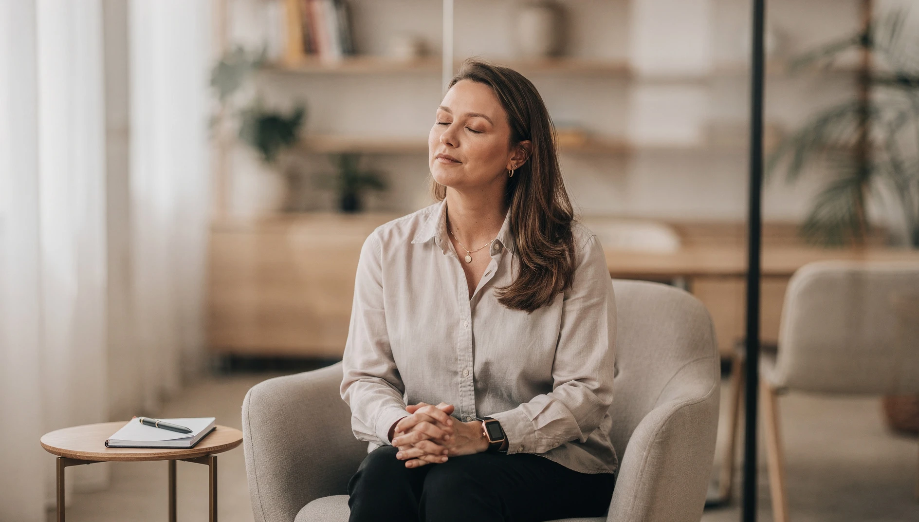 A coach sitting quietly with eyes closed in a peaceful office space in a brief moment of calm